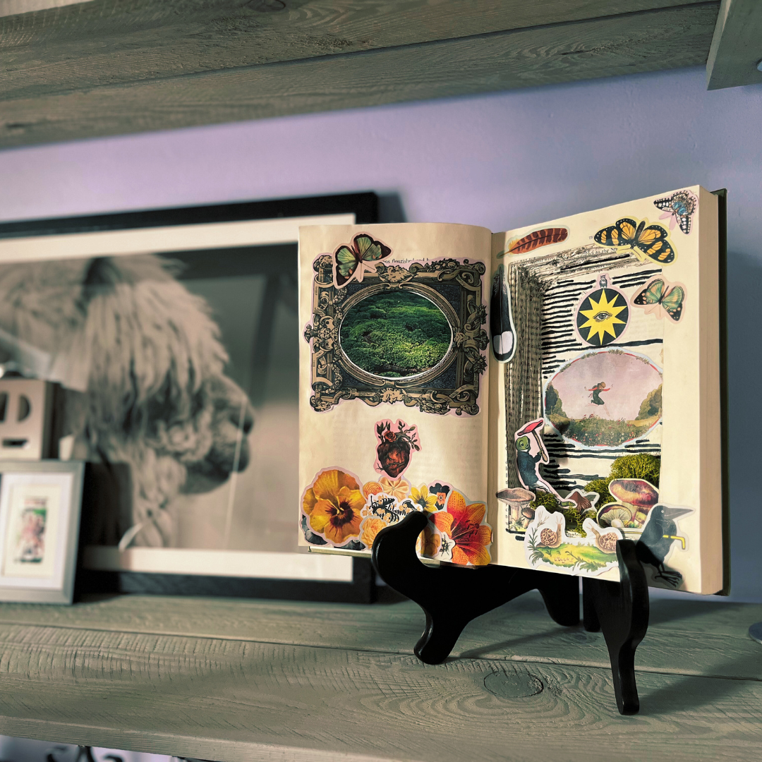 Open book with artistic illustrations on a stand against a blurred background