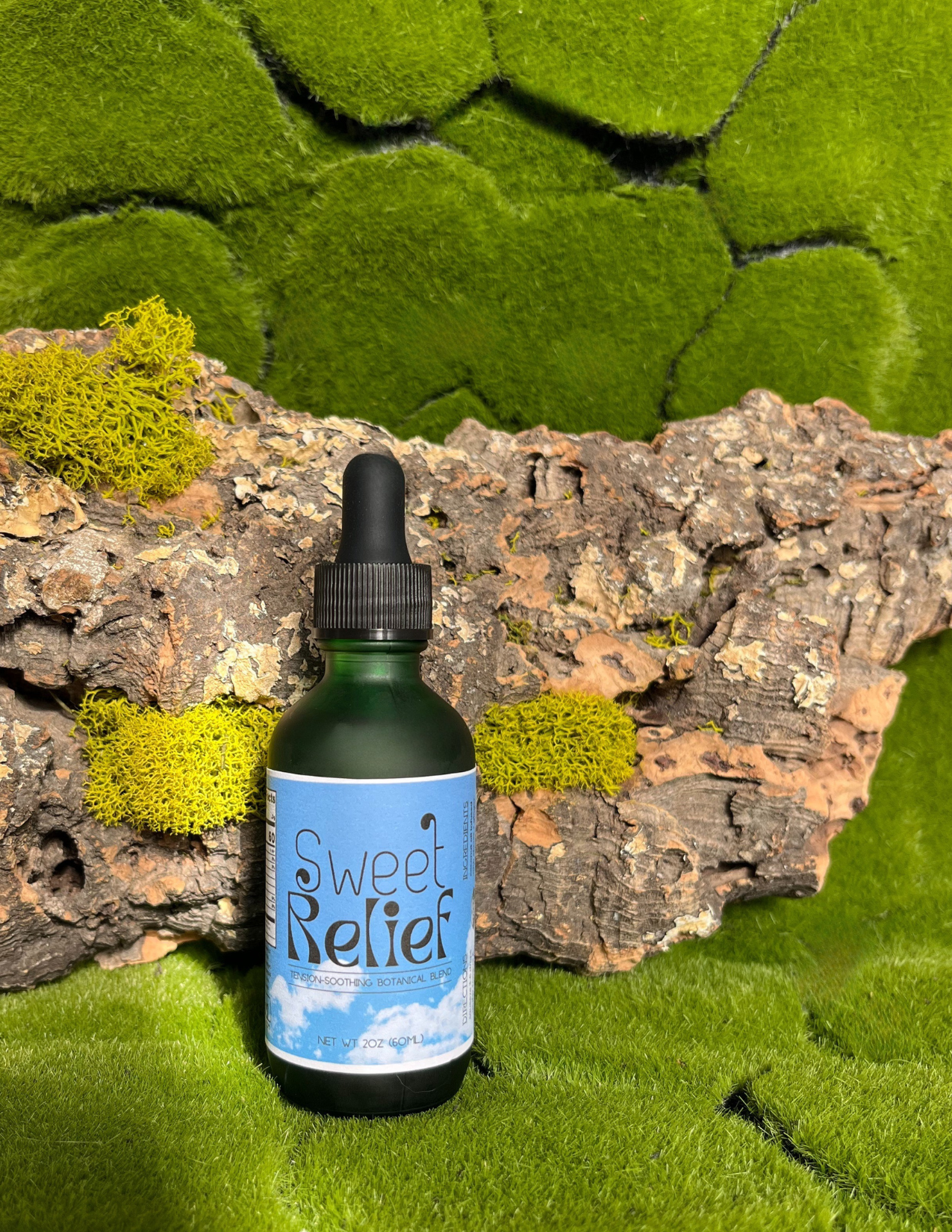 Bottle labeled 'Sweet Relief' on a natural background with green moss and wood.