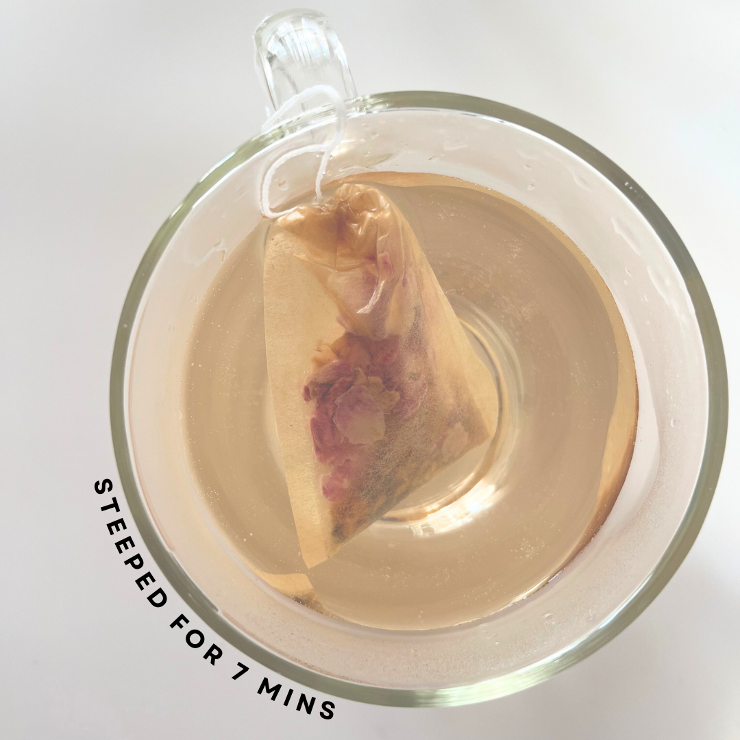 Tea bag steeping in a clear mug with tea liquid, on a white background.