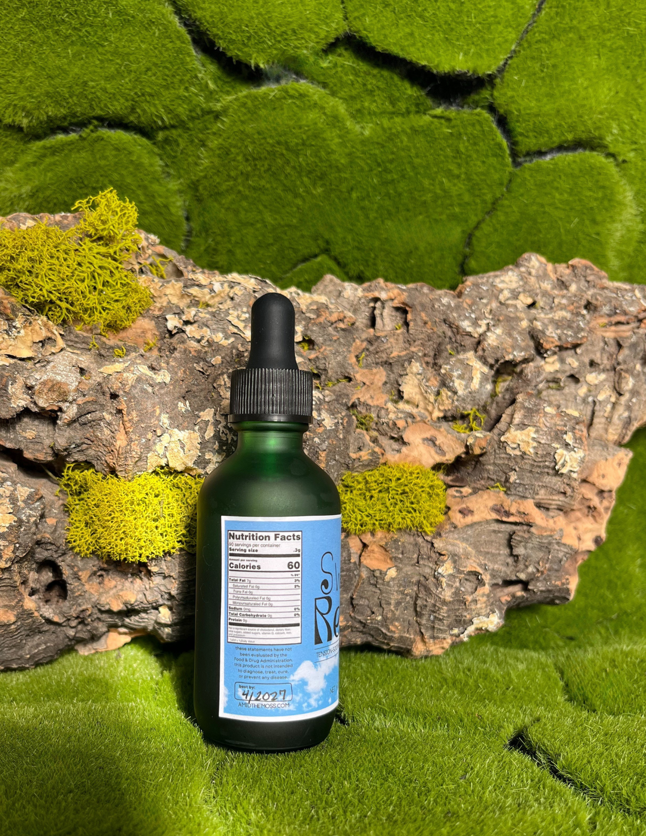 Bottle with dropper on a natural background with moss and wood.