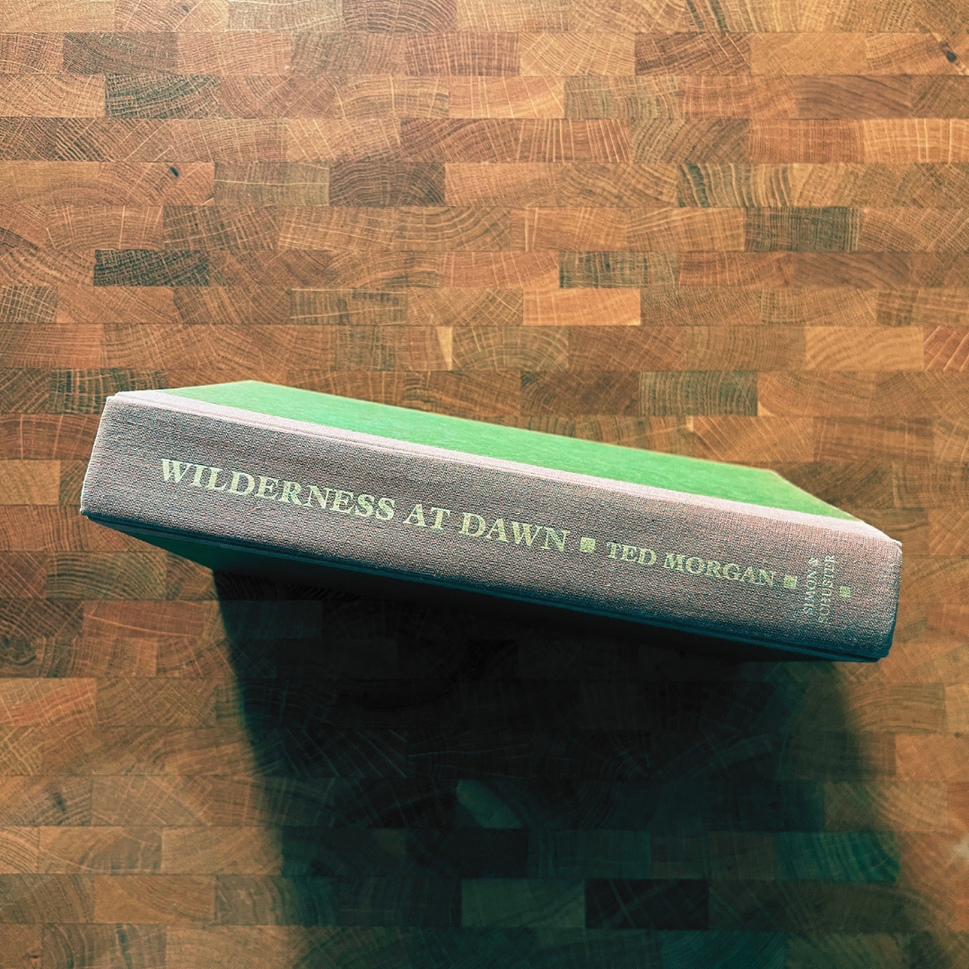 Book titled 'Wilderness at Dawn' by Ted Morgan on a wooden surface