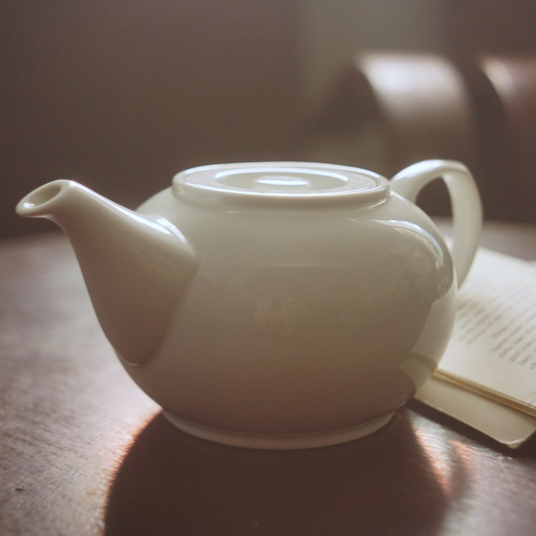 White teapot on a wooden surface with a blurred background