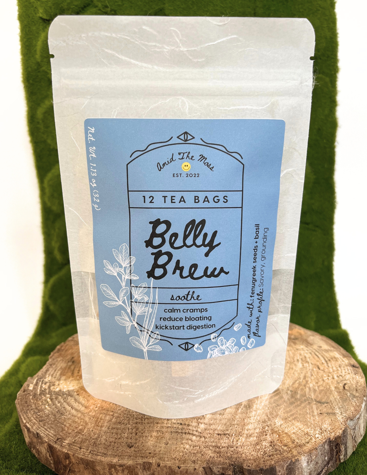 Tea bag package labeled 'Belly Brew' on a wooden block with a green background